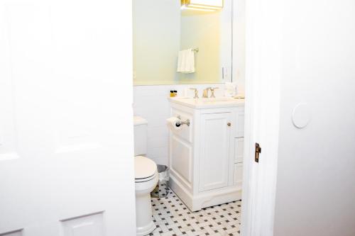 a white bathroom with a toilet and a sink at Three Village Inn in Stony Brook