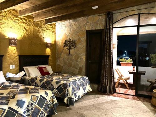 a bedroom with two beds and a stone wall at Hotel & Cava La Parroquia in San Cristóbal de Las Casas