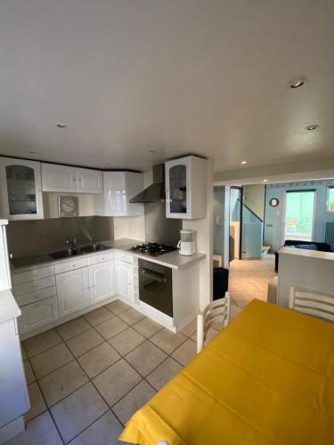 une cuisine avec des armoires blanches et une table dans une pièce dans l'établissement Le Colmarien - hypercentre - free parking - terrasse, à Colmar