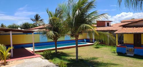 a house with a palm tree and a swimming pool at Dunas Bar&Hotel in Canoa Quebrada