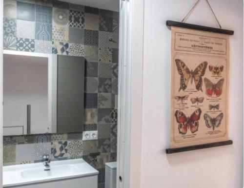 ein Badezimmer mit einem Bild von Schmetterlingen an der Wand in der Unterkunft Brisa Marinera Grupo AC Gestion in Cádiz