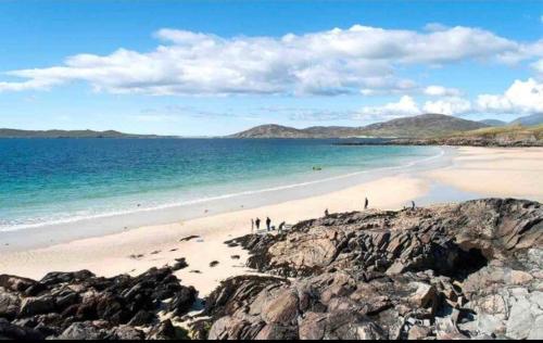 a beach with people walking on the sand and the water at Stornoway Holiday Let in Stornoway