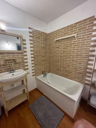 ein Badezimmer mit einer weißen Badewanne und einem Waschbecken in der Unterkunft Charmante maison de ville in Bolbec