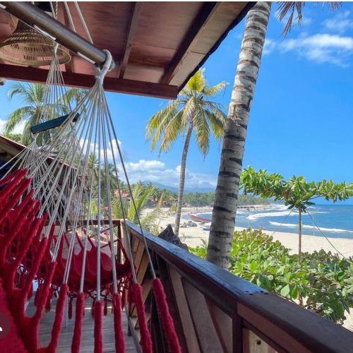 a hammock on a balcony overlooking the beach at Cabaña The Sunset in Santa Marta