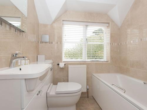 a bathroom with a sink and a toilet and a tub at The Coach House in Wootton Bridge