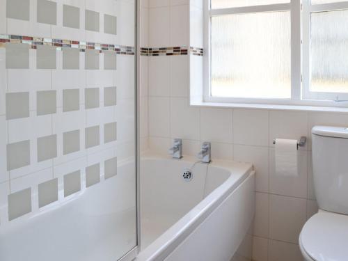 a white bathroom with a tub and a toilet at Avocet Cottage in Sheringham