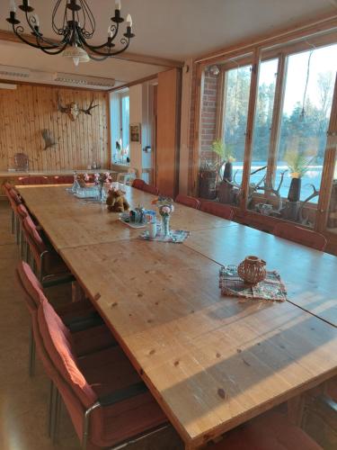 a large wooden table in a dining room with windows at Nederhögen Vildmarkscenter in Rätan