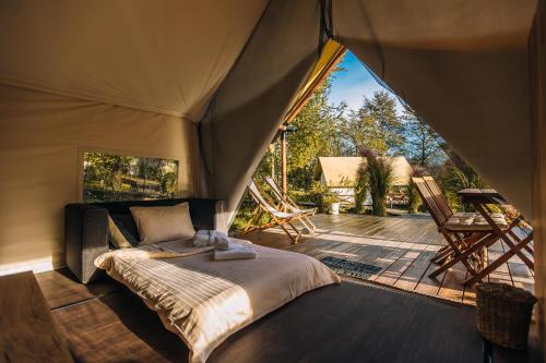 une tente avec un lit dans une chambre avec une terrasse dans l'établissement Luxury vineyard resort Chateau Ramšak, à Maribor