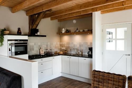 a kitchen with white cabinets and a window at Landelijk gelegen vakantiewoning in Oldebroek