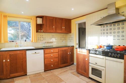 a kitchen with wooden cabinets and white appliances at The Snicket - Traditional Cotswold Home in Cheltenham