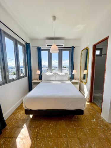 a bedroom with a large white bed with windows at Urbana Hotel in San Juan