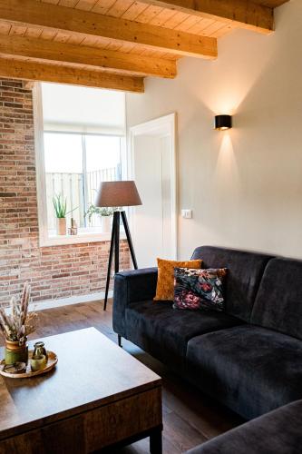 a living room with a black couch and a table at Landelijk gelegen vakantiewoning in Oldebroek