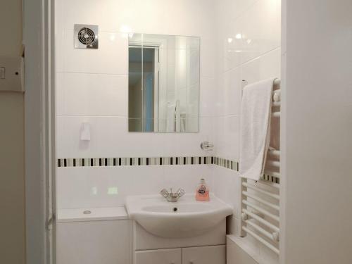 ein weißes Badezimmer mit einem Waschbecken und einem Spiegel in der Unterkunft Rose Farm Cottage in Frostenden