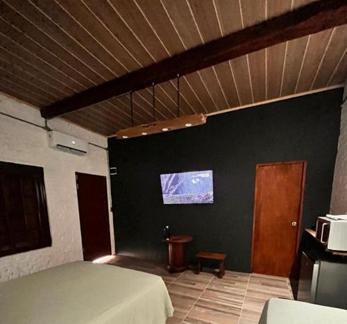 1 dormitorio con 1 cama y TV en la pared en LA POSADA en Aiguá