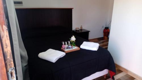 a room with a black bed with white towels and bottles at Complejo San Antonio in Fiambala