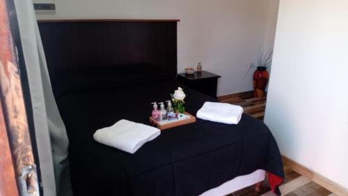 una camera con letto nero, asciugamani e bottiglie bianche di Complejo San Antonio a Fiambalá