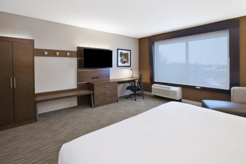 a hotel room with a bed and a flat screen tv at Holiday Inn Express & Suites Okemos - University Area by IHG in Okemos