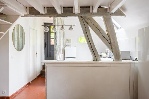 a kitchen with white walls and wooden beams at Le Moulin de Dannemarie in Dannemarie