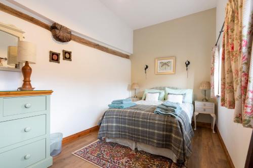 a bedroom with a bed and a dresser at The Chaff House - farm stay apartment set within 135 acres in Bromyard