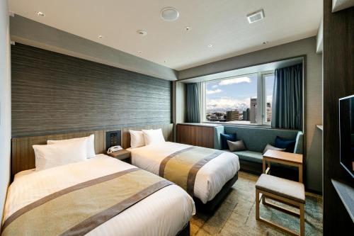 a hotel room with two beds and a window at HOTEL VISCHIO TOYAMA in Toyama