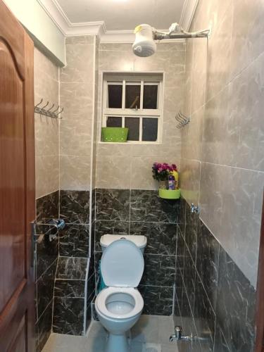 ein Bad mit einem WC und einem Fenster in der Unterkunft Funstay Holiday Homes Nairobi 2 in Nairobi
