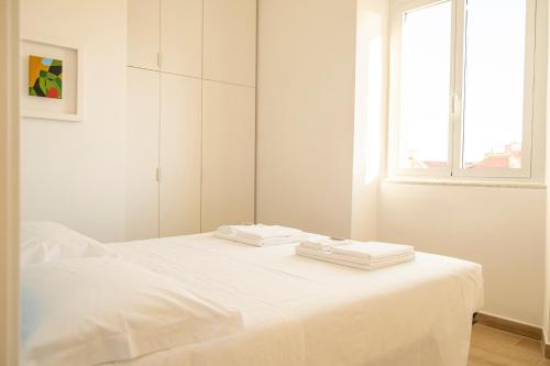 a white bedroom with a bed with two towels on it at Noliday Riviera Sea View Luxury Apartment in Noli