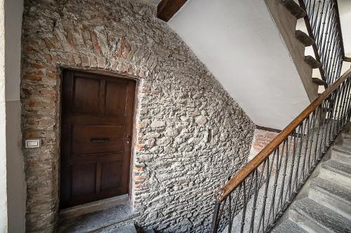 a staircase with a wooden door and a stone wall at Domus Antica Aosta in Aosta