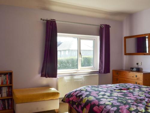 um quarto com uma cama e uma janela com cortinas roxas em Meadow View em Dove Holes