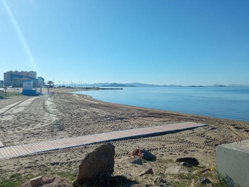 a sandy beach next to a body of water at COMFORT SUITE La Manga, marina & beach in La Manga del Mar Menor