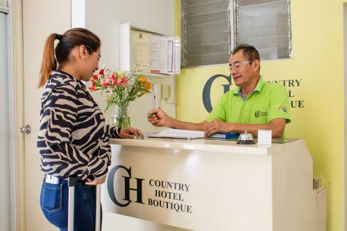Hotel Country Boutique في بيورا: امرأة تتحدث إلى رجل في مكتب الاستقبال