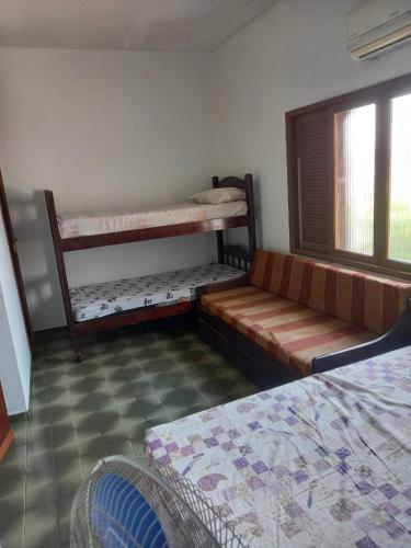 ein Zimmer mit zwei Etagenbetten und einer Couch in der Unterkunft Casa Praia Grande Mirim in Praia Grande