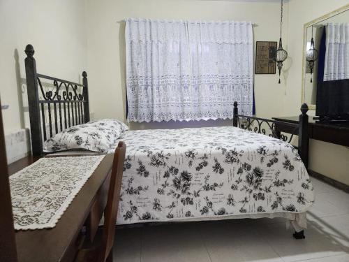 1 dormitorio con cama, mesa y ventana en Pousada mais confortável de Itapema, en Itapema
