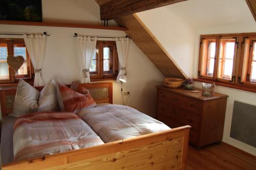 Schlafzimmer mit einem Bett, einer Kommode und Fenstern in der Unterkunft Die Mirnockhütte in Ferndorf