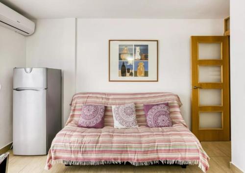 エンプリアブラバにあるApartamento vistas panorámicasのベッドルーム1室(紫色の枕が付くベッド1台、冷蔵庫付)