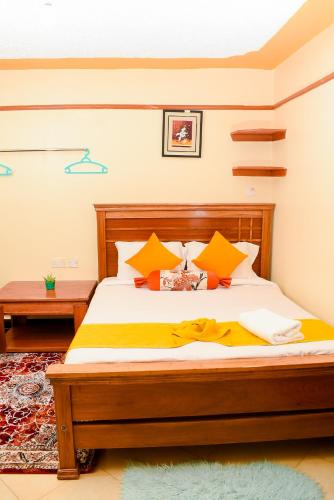 a bedroom with a bed with yellow and orange pillows at Nelly fully furnished studios in Naivasha