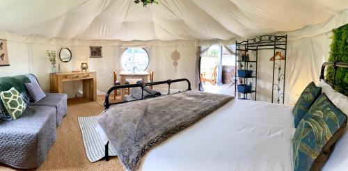 1 dormitorio con 1 cama grande y 1 sofá en Yurt at Le Ranch Camping et Glamping, en Madranges