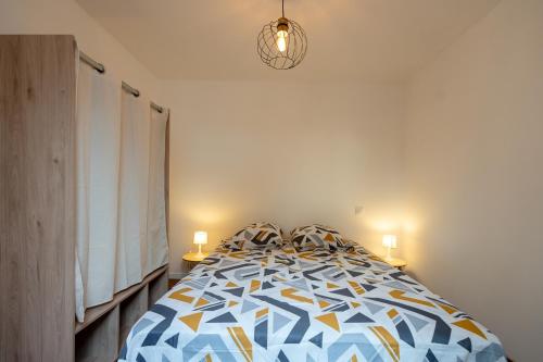 ein Schlafzimmer mit einem Bett mit einer blauen und gelben Bettdecke in der Unterkunft Maison Ohana 4-6 pers dans résidence Privée près de la Plage in Canet-en-Roussillon