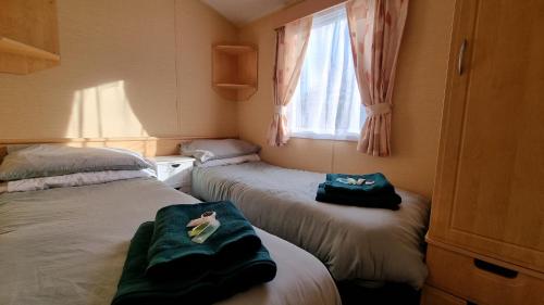 a small room with two beds and a window at The Perrycroft at The Beeches Caravan Park in Gilcrux