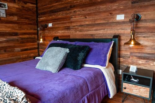 1 dormitorio con cama morada y paredes de madera en Romero Glamping y Cabañas, en Cali