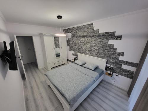 1 dormitorio con cama y pared de piedra en Dacrilo Apartments Cluj-Napoca 12 en Cluj-Napoca