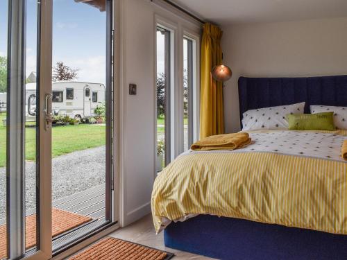 a bedroom with a bed and a sliding glass door at Honeypot Lodge in Ashwater