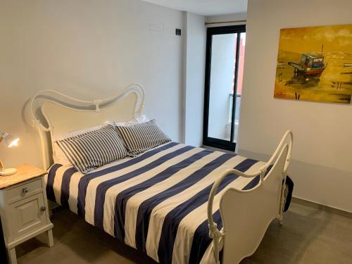 1 dormitorio con 1 cama con edredón a rayas y ventana en Depto a Estrenar 1 dormitorio con balcón en Córdoba