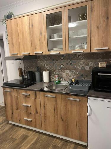 a kitchen with wooden cabinets and a sink at ALFA Apartmani in Subotica