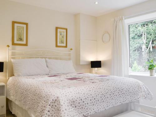 a white bedroom with a bed and a window at Stable Cottage in Carisbrooke