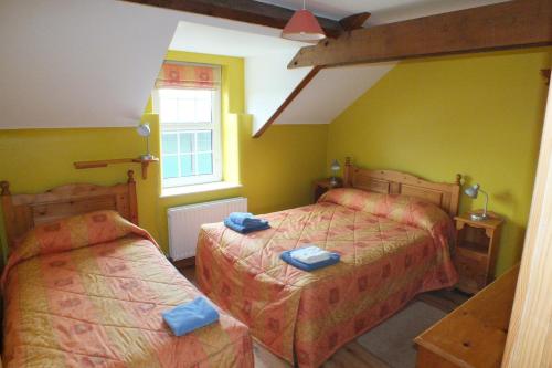 a bedroom with two beds and a window at Barnwell Farm Cottages Corn cottage in Greyabbey