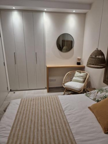 a bedroom with a bed and a mirror and a chair at Poseidon's Limnaria Apartment in Paphos City