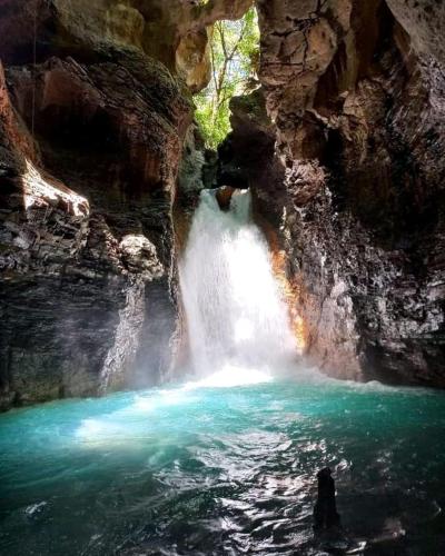 a waterfall in a cave with a pool of water at Pochote Lodge in Hacienda Guayabo