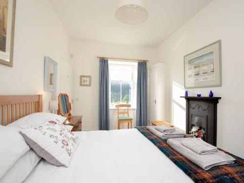 1 dormitorio con cama blanca y chimenea en Nettlebush Cottage-uk5629, en Drummelzier