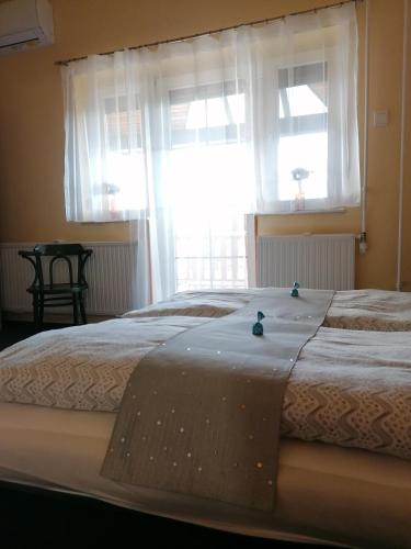 a bed in a bedroom with two windows at Bianco in Sopron