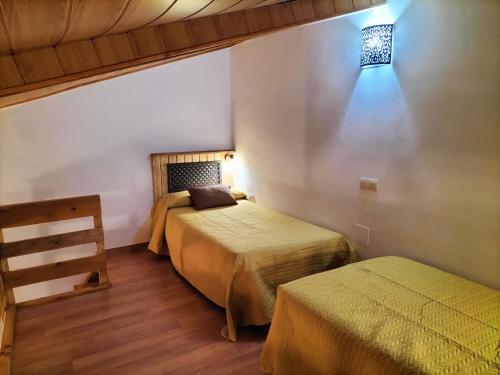ein Schlafzimmer mit 2 Betten und einer Lampe an der Wand in der Unterkunft Don Camino in Villalcázar de Sirga